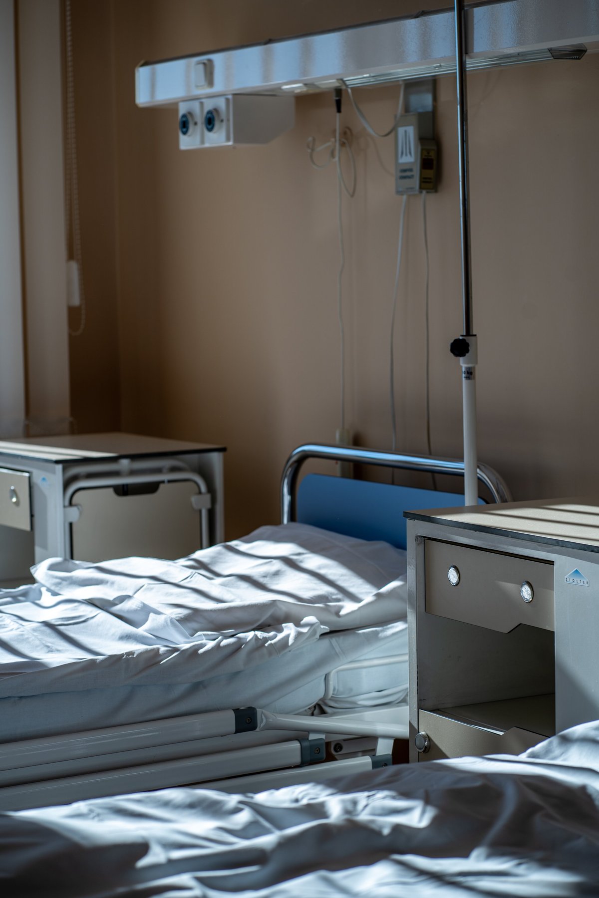Clean hospital bed with bedside table and medical gas panel, an example of the equipment MedGo transports
