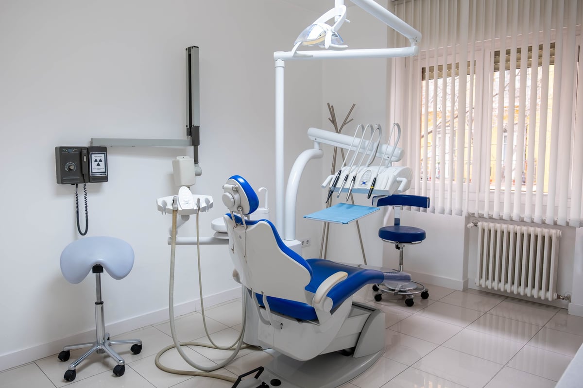 Modern dental chair in a clean dental clinic with X-ray panel and instruments ready for patient care